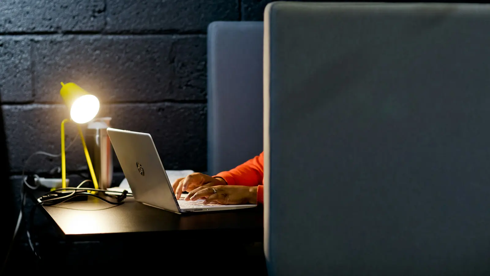 Personne travaillant tard sur un ordinateur portable sous une petite lampe de bureau