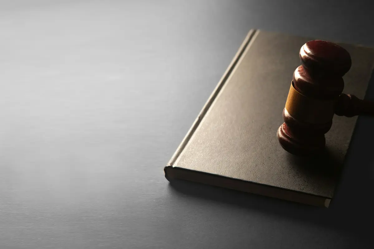 Marteau de juge en bois posé sur un livre fermé, symbole du cadre juridique