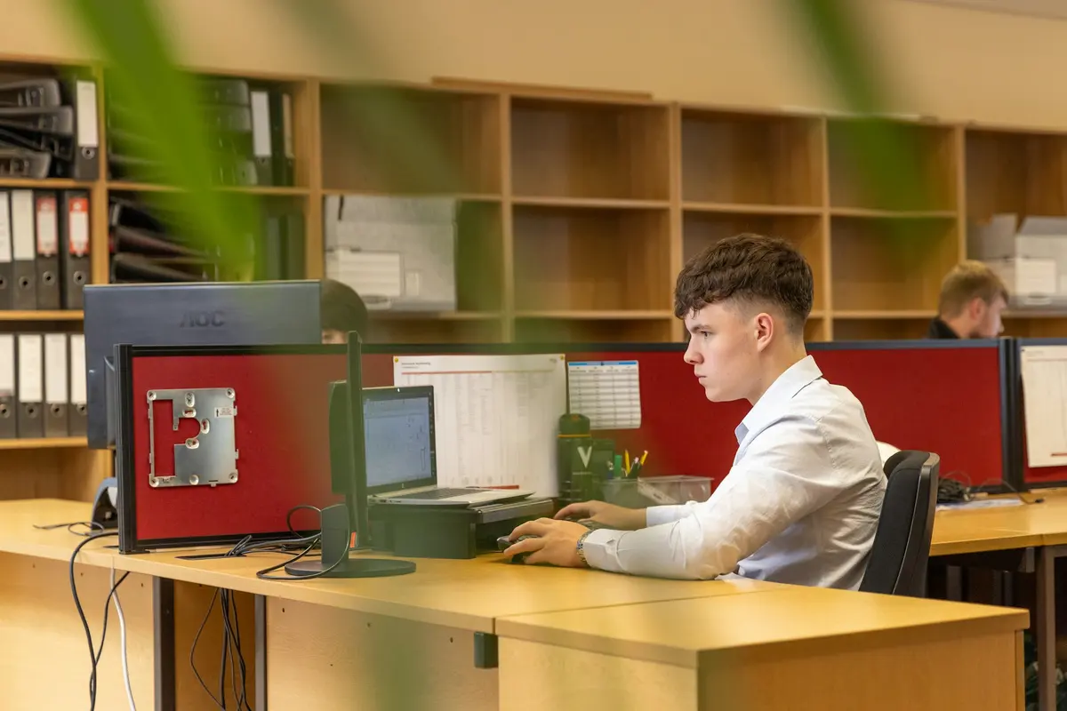 Jeune employé en chemise travaillant sur ordinateur dans un bureau d'ingénierie